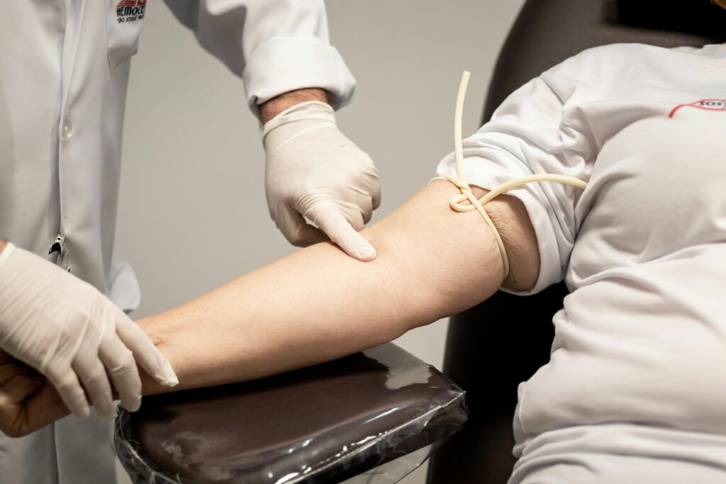Medical professional wearing gloves preparing patient for blood draw using a tourniquet.